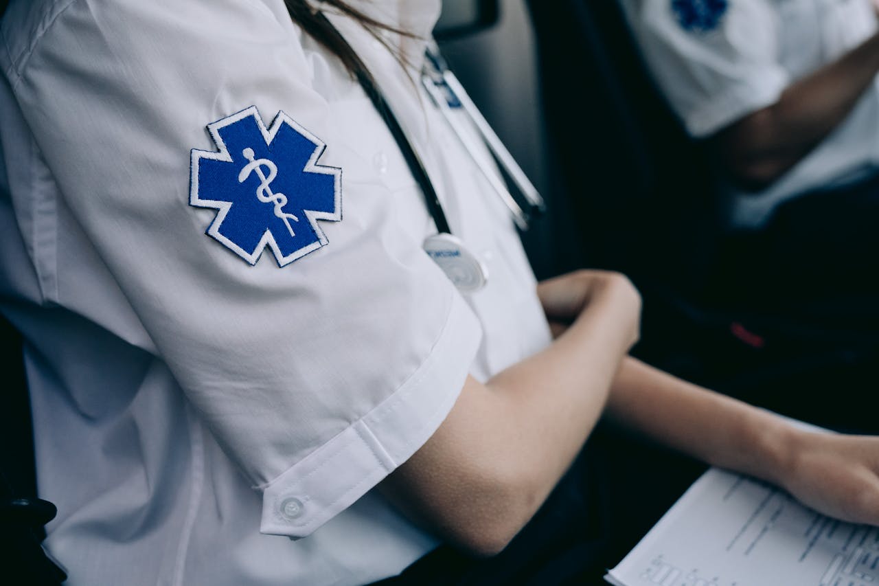 Paramedics in uniform work with medical charts inside an ambulance.