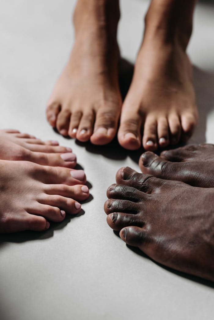 Close-up of diverse feet together on a white surface, representing unity and diversity.